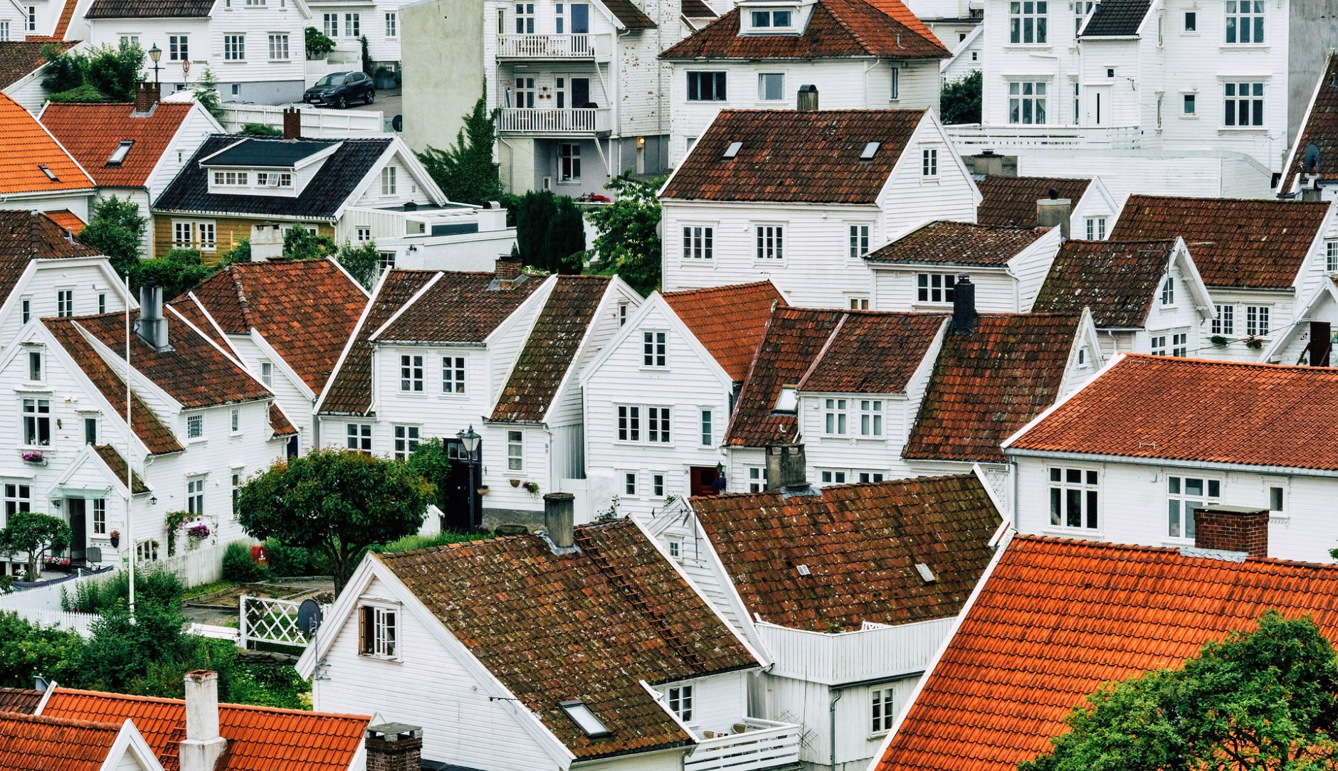 Ein Foto von dicht aneinanderstehenden, weißen Häusern mit roten Ziegeldächern, die sich einen Hang hinaufziehen.