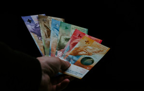 Eine Hand, die alle sechs verschiedenen Schweizer Banknoten gefächert in einer Hand hält