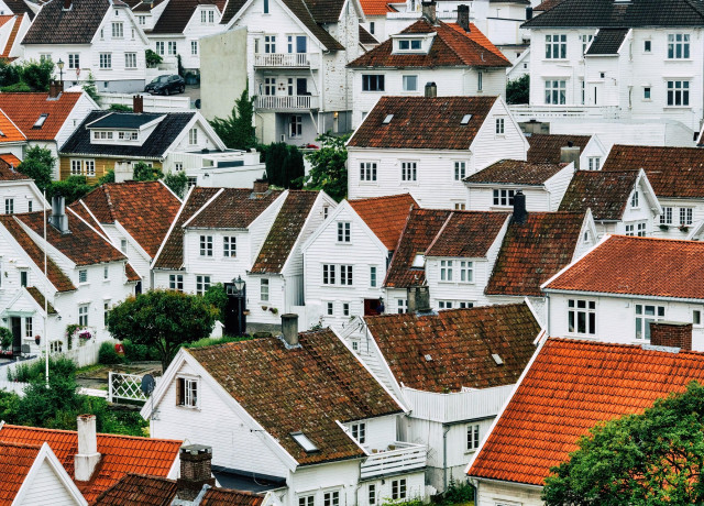 Ein Foto von dicht aneinanderstehenden, weißen Häusern mit roten Ziegeldächern, die sich einen Hang hinaufziehen.