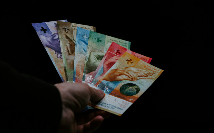 Eine Hand, die alle sechs verschiedenen Schweizer Banknoten gefächert in einer Hand hält
